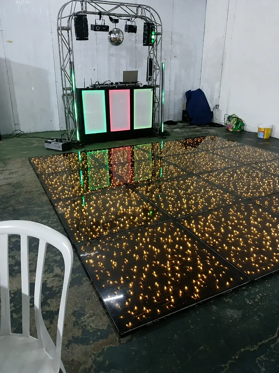 Pista de LED infinita pronta para a festa. Módulos com pontos de luz dourados criam efeito de profundidade em frente à estrutura do DJ.